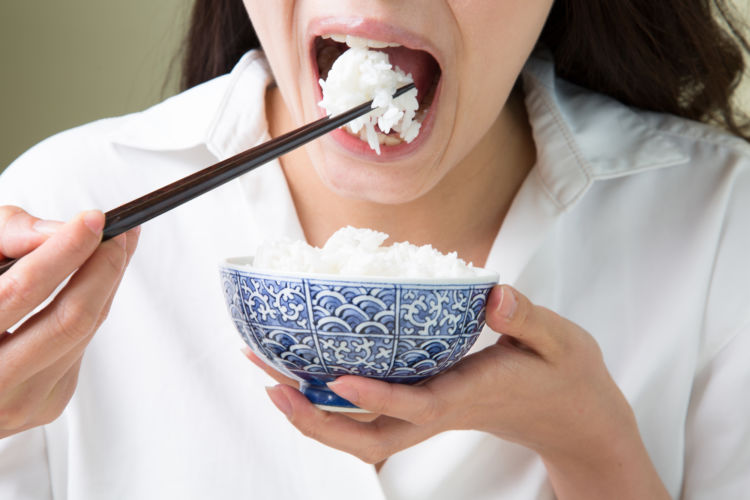 アミラーゼを持つ白米を食べる女性