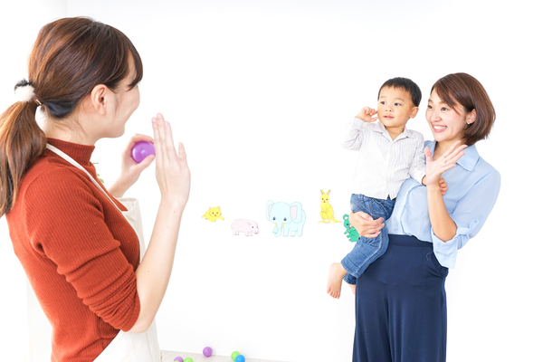 保育士さんに手を振る保護者と子ども