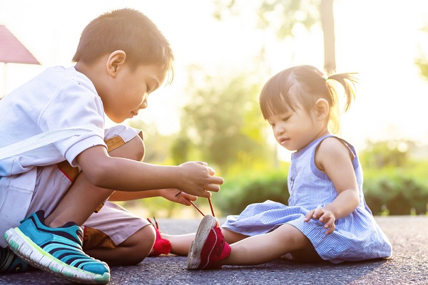 男の子が女の子の靴紐を結んでいる様子