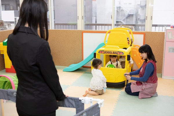 子どもを見ているスーツの女性