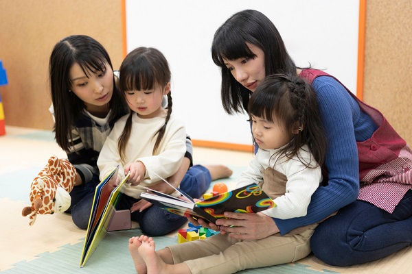子どもに絵本を読んでいる保育士