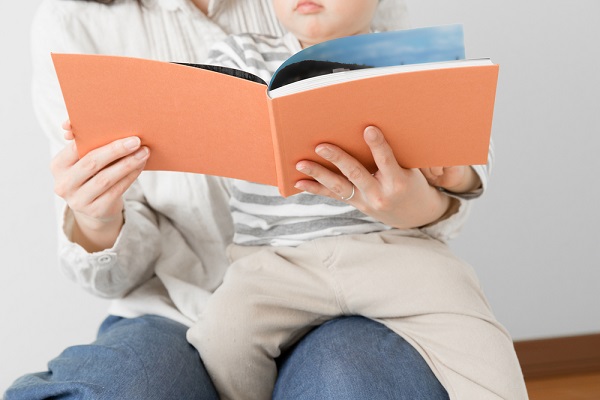 赤ちゃんに絵本を読んでいる女性