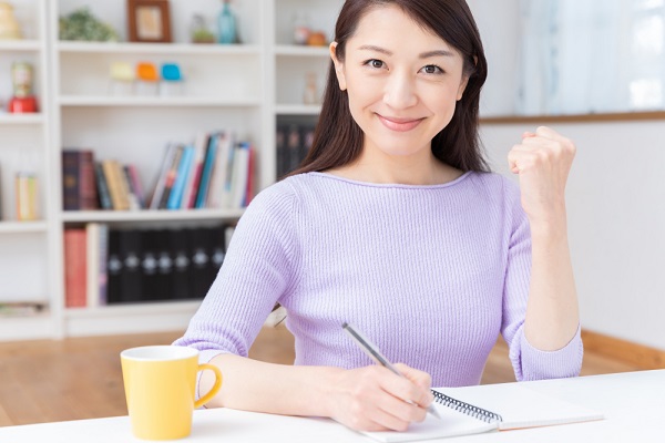 書類を書きながらガッツポーズをしている女性の写真