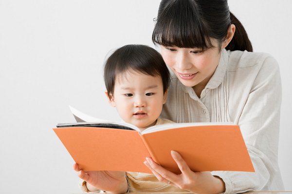 子どもに絵本を読んでいる女性