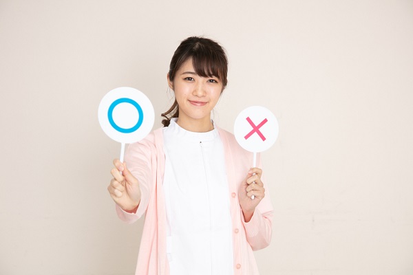 〇✕の札を持った女性
