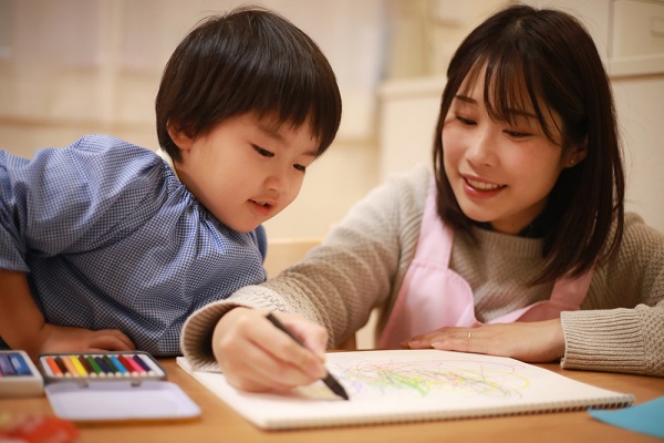 子どもと絵を描く保育士さん