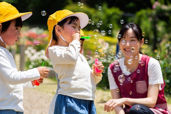 シャボン玉で遊ぶ保育士と子ども
