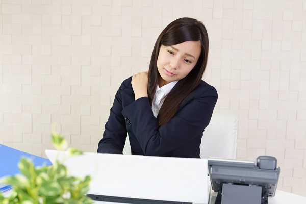 肩がこるスーツの女性
