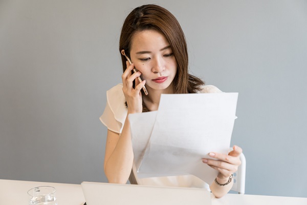 紙を見ながら電話する女性