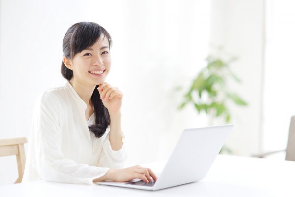 笑顔でパソコンの前に座る女性