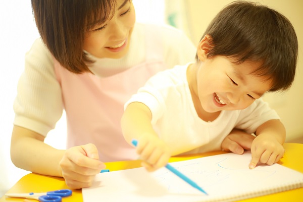絵を描く子どもと保育士
