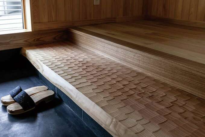 玄関の式台には、一枚板の青森スギを使用。職人が手仕事で仕上げた表面のなぐり加工は、見た目の美しさに加え、足触りの良さを高める効果も【くふうイ