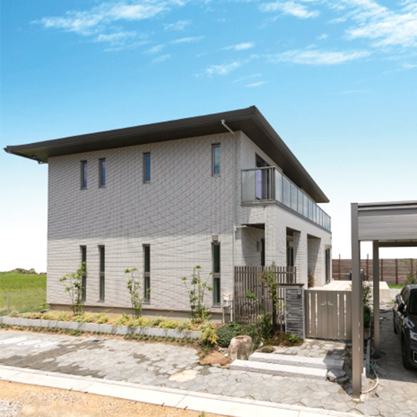 パナホーム愛岐｜モダンなデザインの二階建て住宅の外観。シンプルながらも洗練された構造が、開放感ある周囲の景観と調和している。