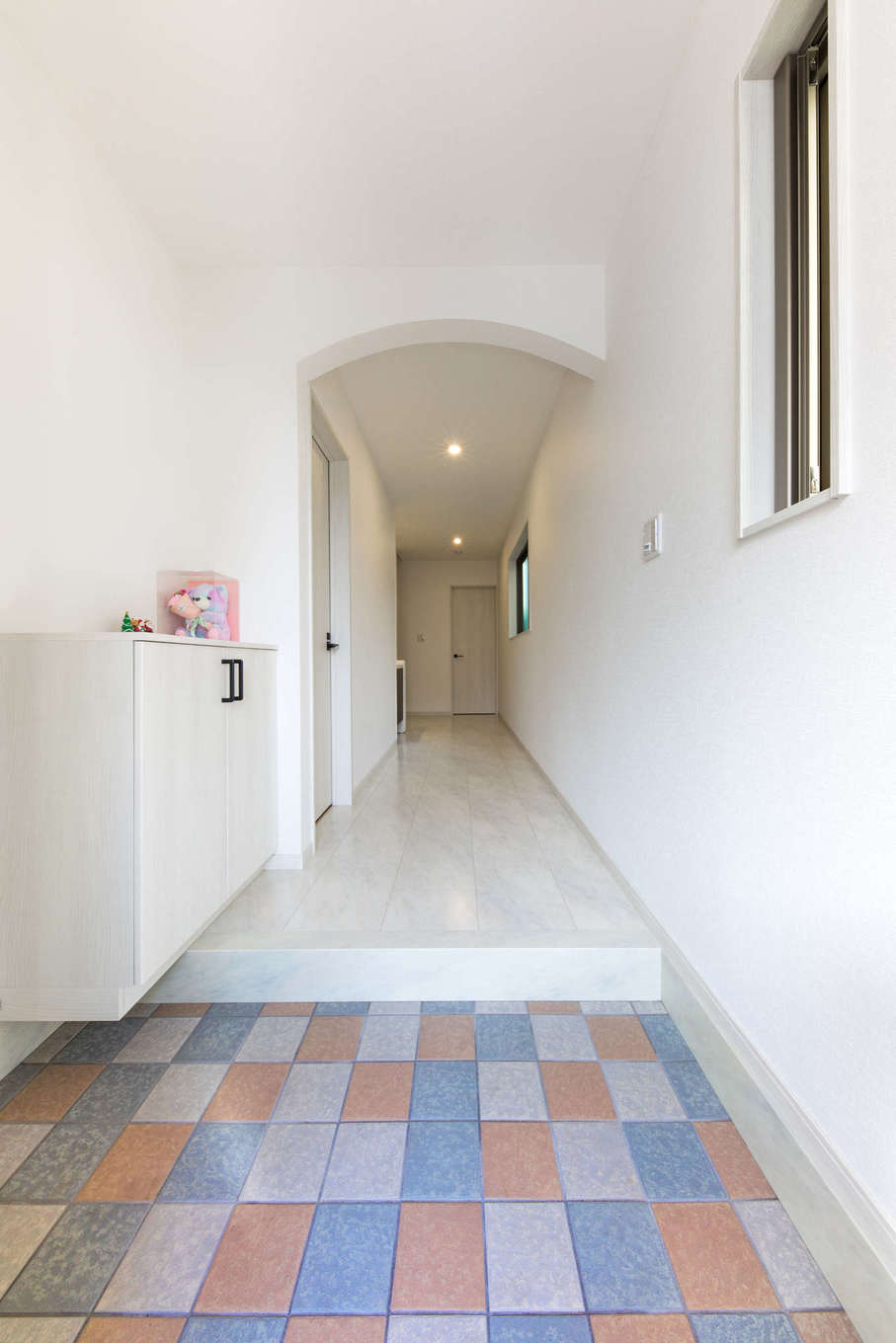 玄関ポーチとお揃いのタイルで 外との一体感を持たせた玄関ホール ホールにはldkと同じ大理石調の床材を 緩やかな角度のアーチの垂れ壁が落ち着