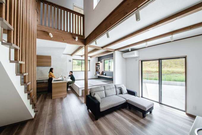 吹き抜けのあるldk リビング階段の手すりや化粧梁を無垢材で統一し ダイナミックで上質感あふれる空間が実現 L型のオープンキッチンはテーブル