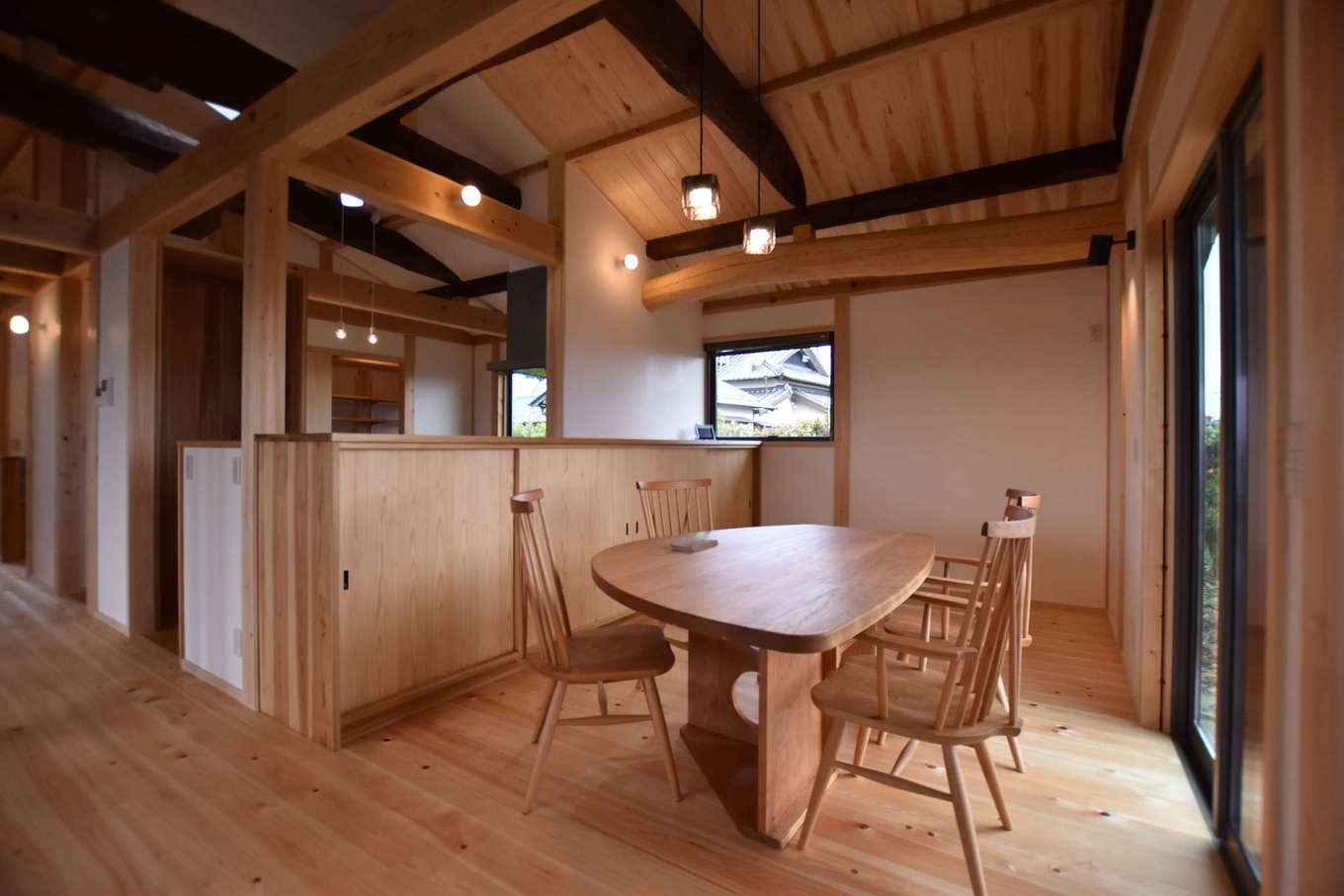 ダイニングに設けた掃出窓の先にはウッドデッキがあり 自然を身近に感じながら心ゆたかな暮らしを楽しめる キッチン側の収納棚をはじめ 室内には適