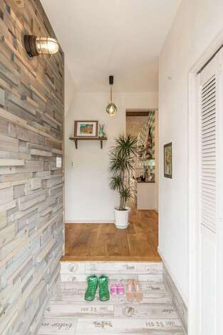 凹凸感のあるウッドパネルと英字がプリントされたタイルでまとめた玄関 キーケースの扉には結婚式のブーケのドライフラワーが使われ 思い出も溶け込