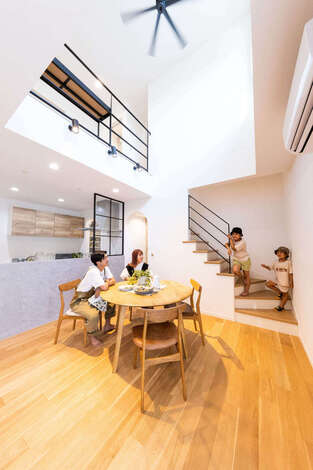 吹き抜けのダイニングスペース モルタル仕上げのキッチン腰壁や アイアンの階段の手すりなど 細部に夫妻のこだわりが反映されている 階段は玄関か