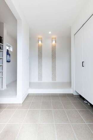 来客の目に留まる玄関の正面 ライトと柄クロスで高級感を演出 扉なしのシューズクロークは視線が抜けて空間を広く見せられる イエタテ