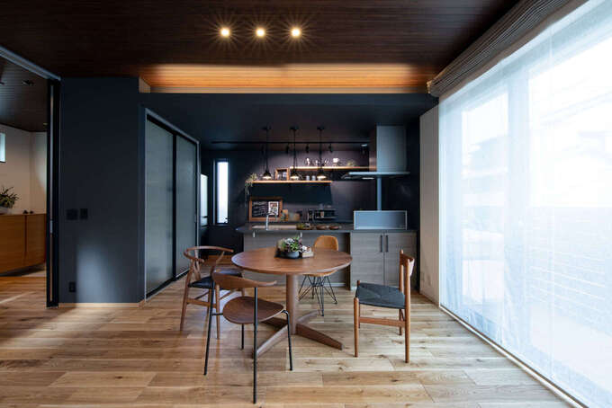 街角にある おしゃれなカフェをイメージしたオープンキッチン 丸テーブルと椅子もカフェっぽくコーディネート 黒い建具のパントリーが空間を引き締