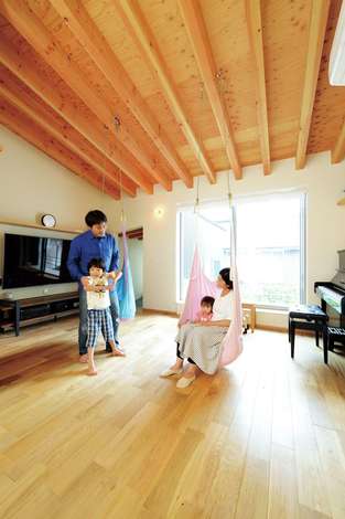 床にも天井にも無垢材を使用した子世帯のldk 配線を隠せるtvボードを造作し 空間をすっきりと見せる 中庭の景色もリビングの一部として楽しめ