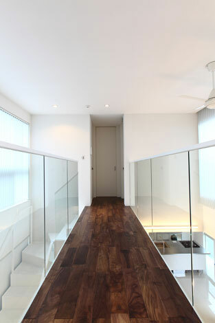 吹抜けに橋を架けたかのような2階の廊下は プライベートルームと洗面 浴室スペースをつないでいる 両側の手すり部分にスケルトンガラスを用い 明