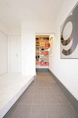 真っ白な壁と床に 三和土のグレーが映える玄関 奥の収納には ご主人が集めているnikeのスニーカーがずらり イエタテ