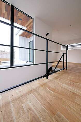 黒いアイアンの手すりのシンプルなラインが美しい階段ホール 2階の床はウォルナットのナチュラル色で統一 イエタテ