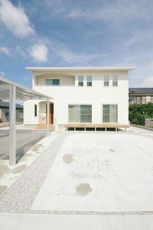 真っ白な外観に木目調の玄関が映える 2階はベランダの垂れ壁をｒにし 上げ下げ窓を採用することで外観もかわいらしく イエタテ