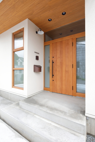 ドアや軒天 窓枠の木質と モルタルの質感がマッチした玄関ポーチ ライトは雑貨好きの奥さまがチョイス イエタテ