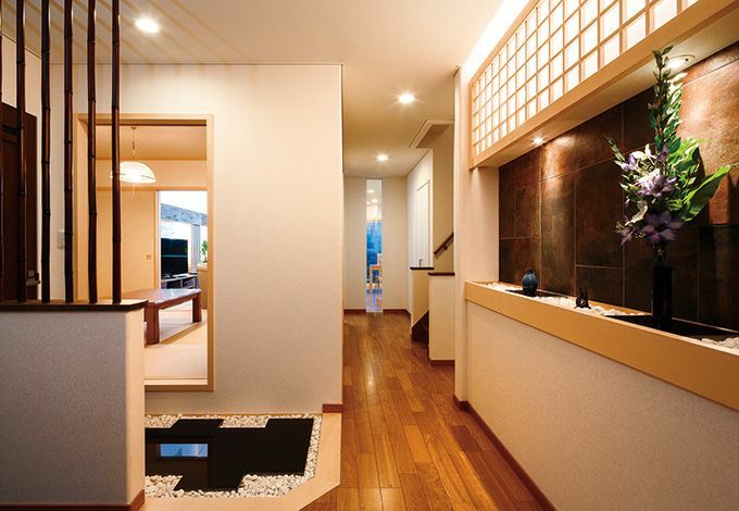 高級感ただよう玄関ホールから廊下をのぞむ 真っ直ぐ進むとリビングダイニング 左側が和室 トイレへの動線は黒御影石と竹の格子でアクセントをつけ