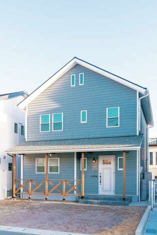 温かみのあるラップサイディングの外壁と 玄関にはカバードポーチ 真っ白な窓枠が印象的なアメリカンハウスは 西海岸にあるサーファーズハウスのイ