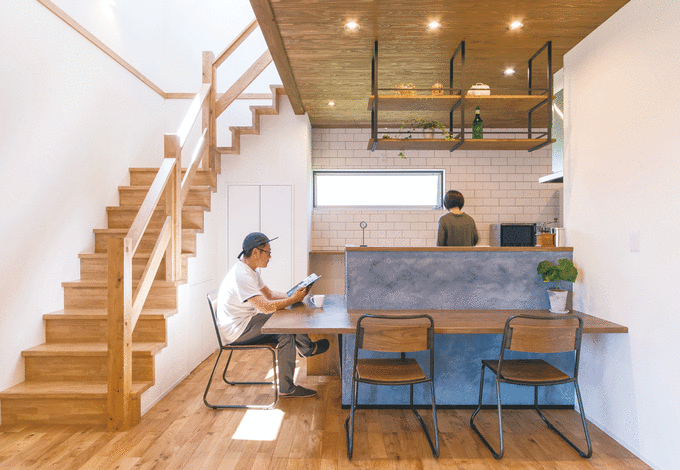 吹き抜け上部の窓から光が降り注ぐダイニングキッチン 無骨なインダストリアルスタイルだが 清潔感のある白いタイル 木の柔らかい雰囲気に女性らし