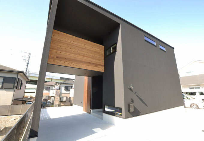 黒色の塗り壁がモダンな外観に木製のインナーテラスが映える 玄関前をインナーガレージにすることで雨の日でもぬれずに家の中に入ることができる イ