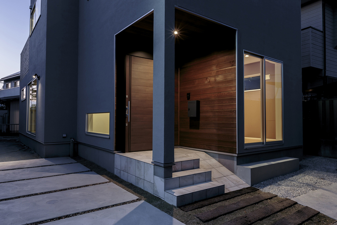 玄関ポーチの外壁は無垢板張りに 塗り壁の外壁と調和し 重厚感と温かみのある雰囲気を演出 自転車やカートを土間に上げやすいようにスロープも設け