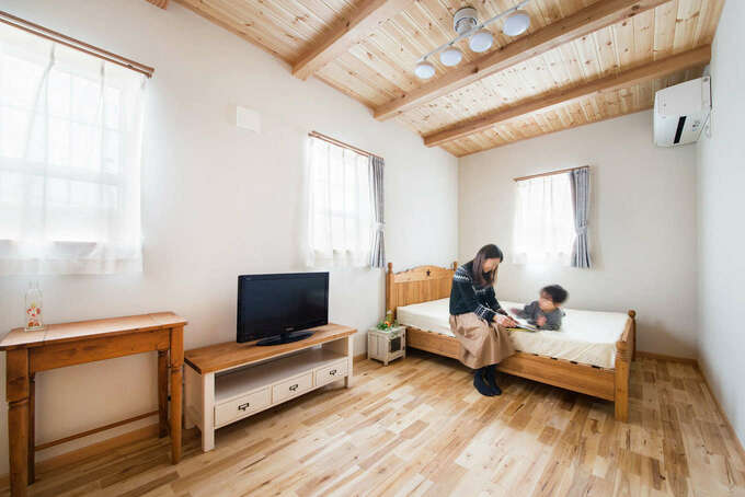 梁を現しにしたパイン材の勾配天井に癒される主寝室 レースのカーテンと上げ下げ窓の組み合わせが合う家づくりも 今井建設 の特徴 ウォークインク