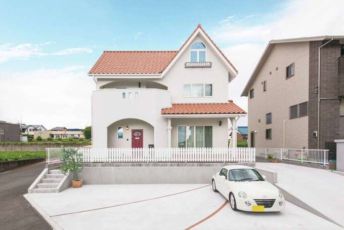 奥さまの子どもの頃からの夢を叶えたプロヴァンススタイルの外観 緑豊かなロケーションで オレンジの瓦と白い壁が青い空にくっきりと映える 駐車場