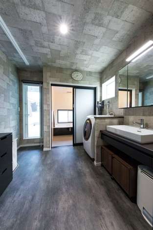 ご主人が最もこだわった2階の浴室 裸のままバルコニーに出られるよう腰壁を高くした 手前はランドリールームで 洗濯 部屋干し アイロンまでがこ