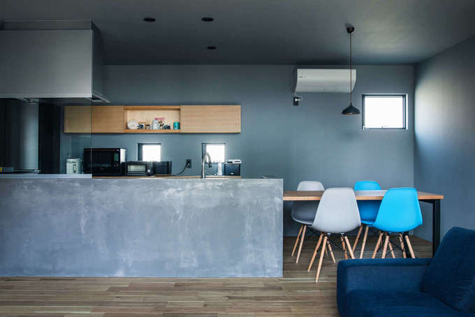 壁付けのキッチンを腰壁で囲み アイランド風に仕上げたオープンキッチン モールテックスを塗って仕上げたモルタル調の壁と アイアンの脚を持つ造作