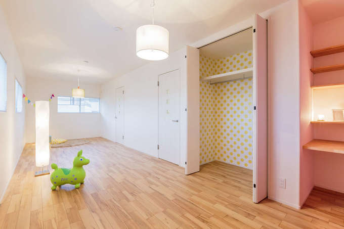 広々として開放的な2階の子ども部屋 ドアを2か所設けて 将来2部屋に仕切れるようになっている 白い空間にピンクのアクセントクロスが映え やさ