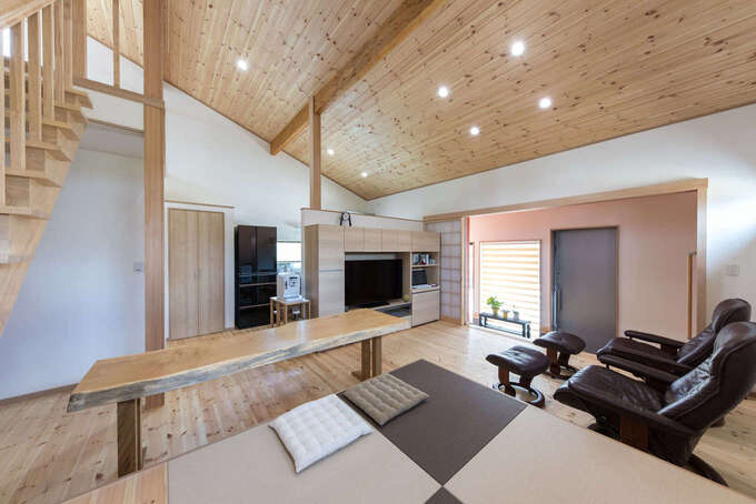 床と勾配天井にパイン材を用いたldk 収納棚とパソコンコーナーも兼ねた造作のテレビボードをキッチンとの仕切りに 小上がりの畳コーナーを椅子が