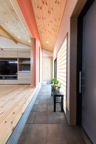 玄関土間からそのままリビングへ上がる 土間はキッチンまで続いているので 買い物帰りの奥さまにも優しい動線 壁は木の風合いに合う明るいえんじ色 玄関土間からそのままリビングへ上がる 土間はキッチンまで続いているので 買い物帰りの奥さまにも優しい動線 壁は木の風合いに合う明るいえんじ色