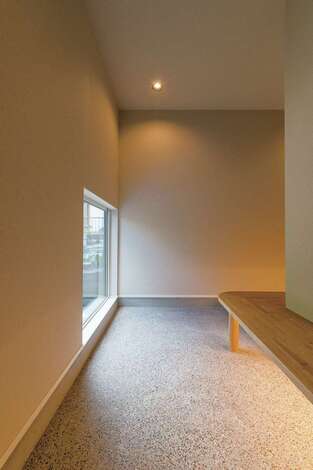 地窓から明かりが入るゆったりとした広さの玄関土間には L字型にベンチを造作 来客と腰掛けておしゃべりも 夜は間接照明で落ち着きある佇まいに