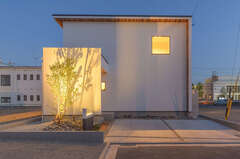 玄関の上に張り出した木のポーチ屋根が白い塗り壁の外観にぬくもりを添える イエタテ