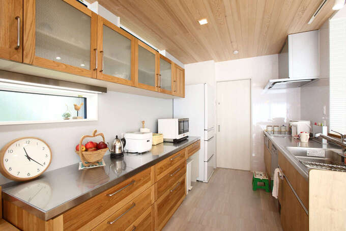 ご主人も料理を手伝うので キッチンの作業スペースを広くとった 食器棚も無垢材で造作 3回分の食器を一度に洗浄できる食洗機 ミーレ が 働く奥