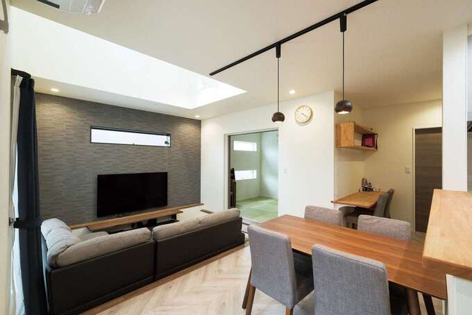 テレビ背面の壁は濃色のエコカラットで男前な仕上がりに ダイニング後方には将来子どもの勉強場所にするカウンターを設置 イエタテ