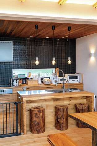 夫婦で並んで料理ができるように製作したキッチン 丸太の椅子は 取り壊した家の梁をリメイクしたもの イエタテ