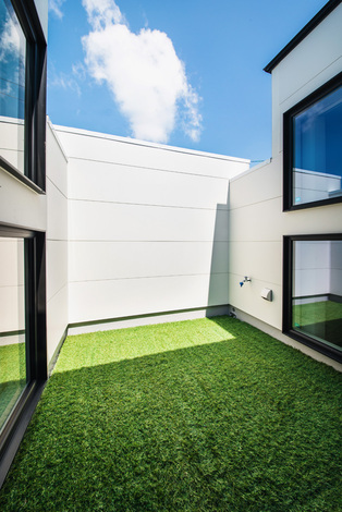 壁を高くしてプライバシーを確保したバルコニー 人工芝を敷いて 自分たちだけのプライベート ガーデンを実現 ダイニングと畳スペースに窓を設け