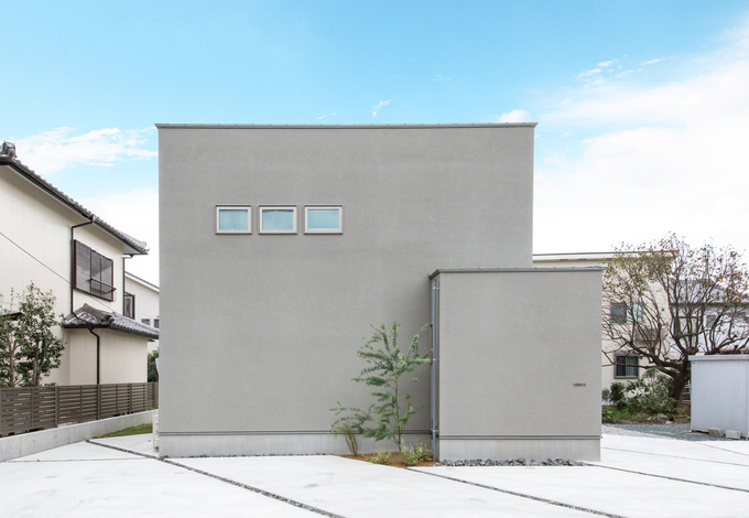 通路側からの視線を遮るように 玄関ポーチを壁で四角く囲ってあるため 大小の箱を2つ並べたような個性あふれるフォルムが実現 窓の配置も均整が取