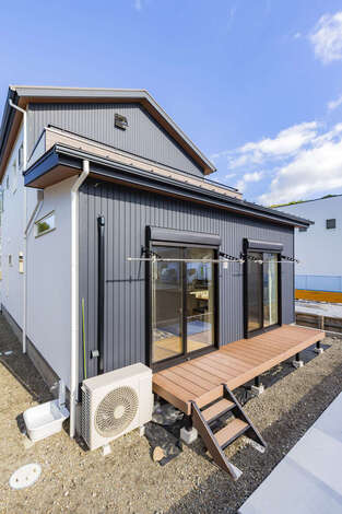 奥まった庭側にはウッドデッキを 外壁はダークカラーのサイディングを用いて ご主人の好みの男前な雰囲気に 正面との印象とのギャップも楽しい イ